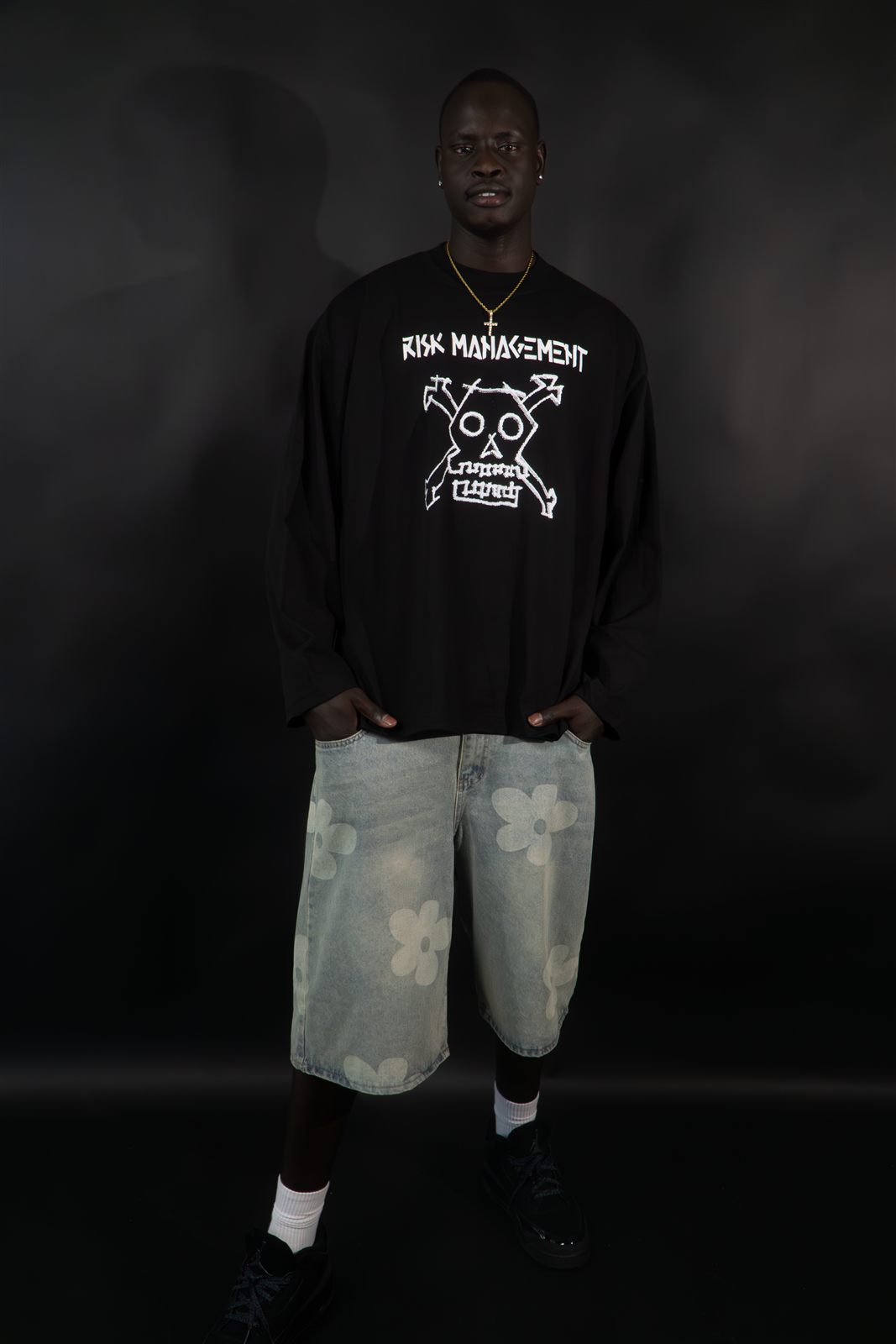Model wearing the Crossbones Longsleeve graphic tee, white ink skull-and-crossbones design on black cotton