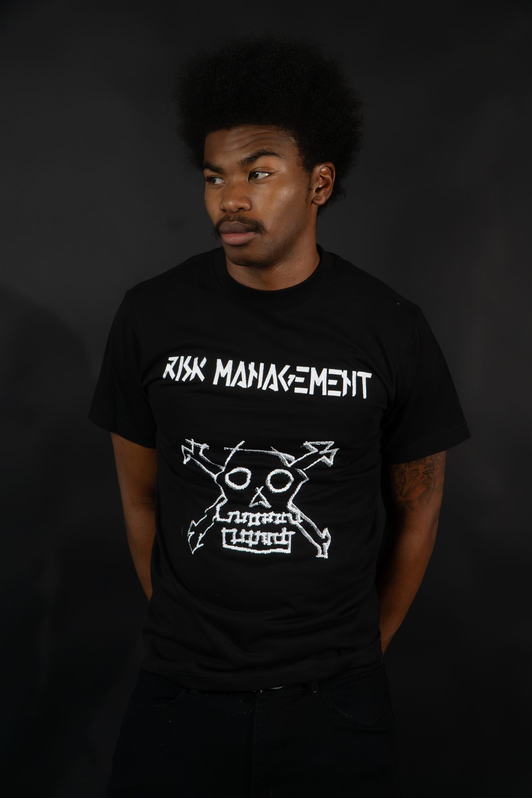 Model wearing the Crossbones Shortsleeve graphic tee, white ink skull-and-crossbones design on black cotton